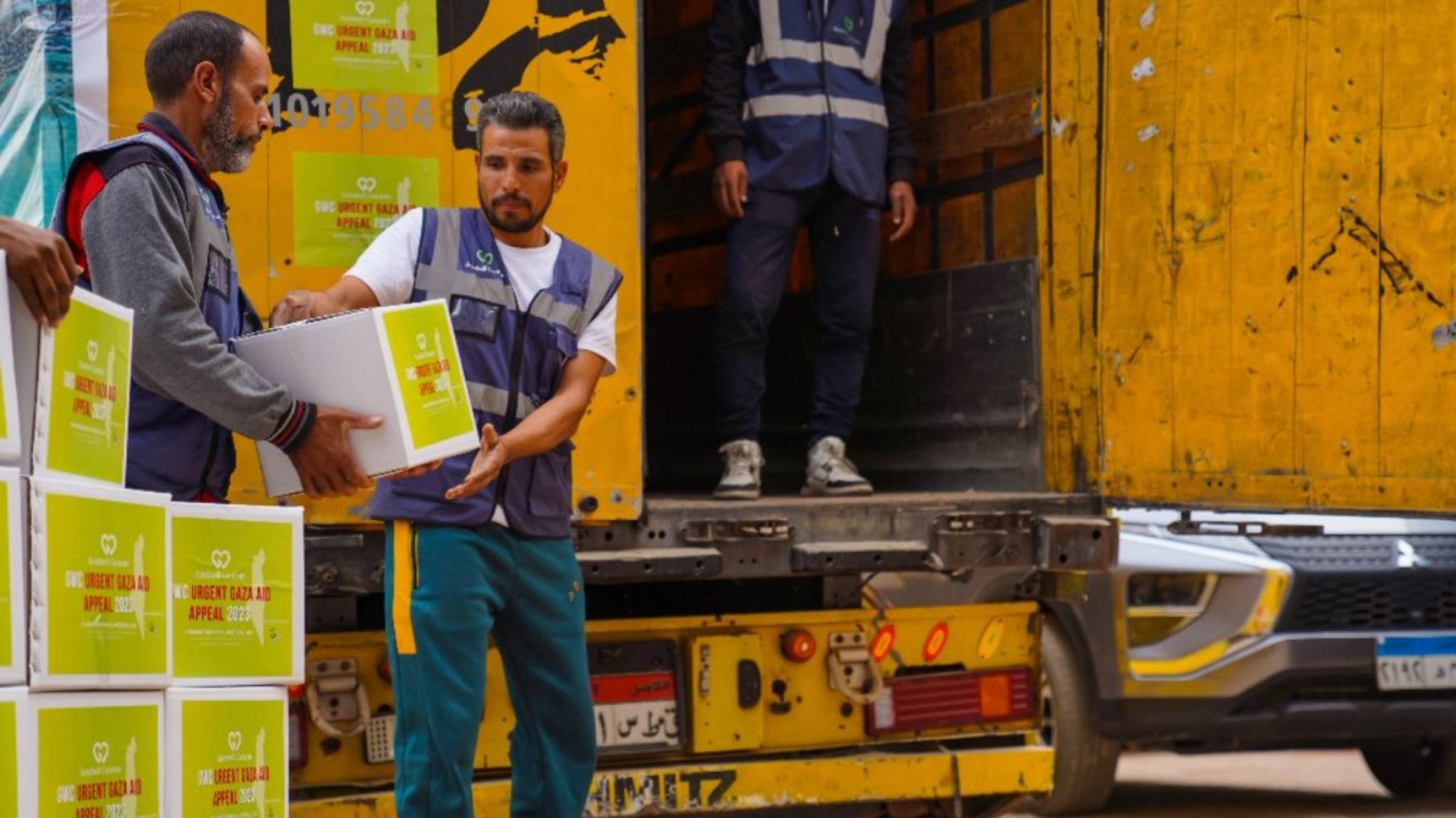 Drei Männer beladen einen Hilfstransport für Gaza