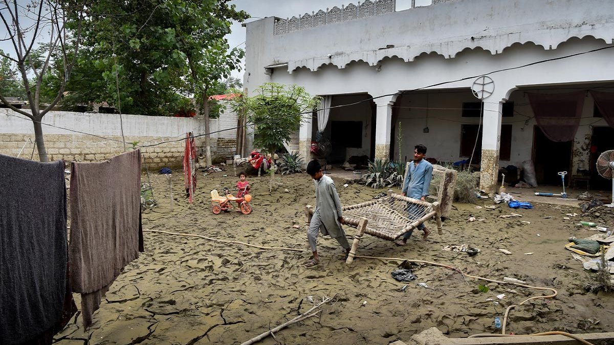 Zwei Kinder tragen Möbel aus einem Haus in Pakistan