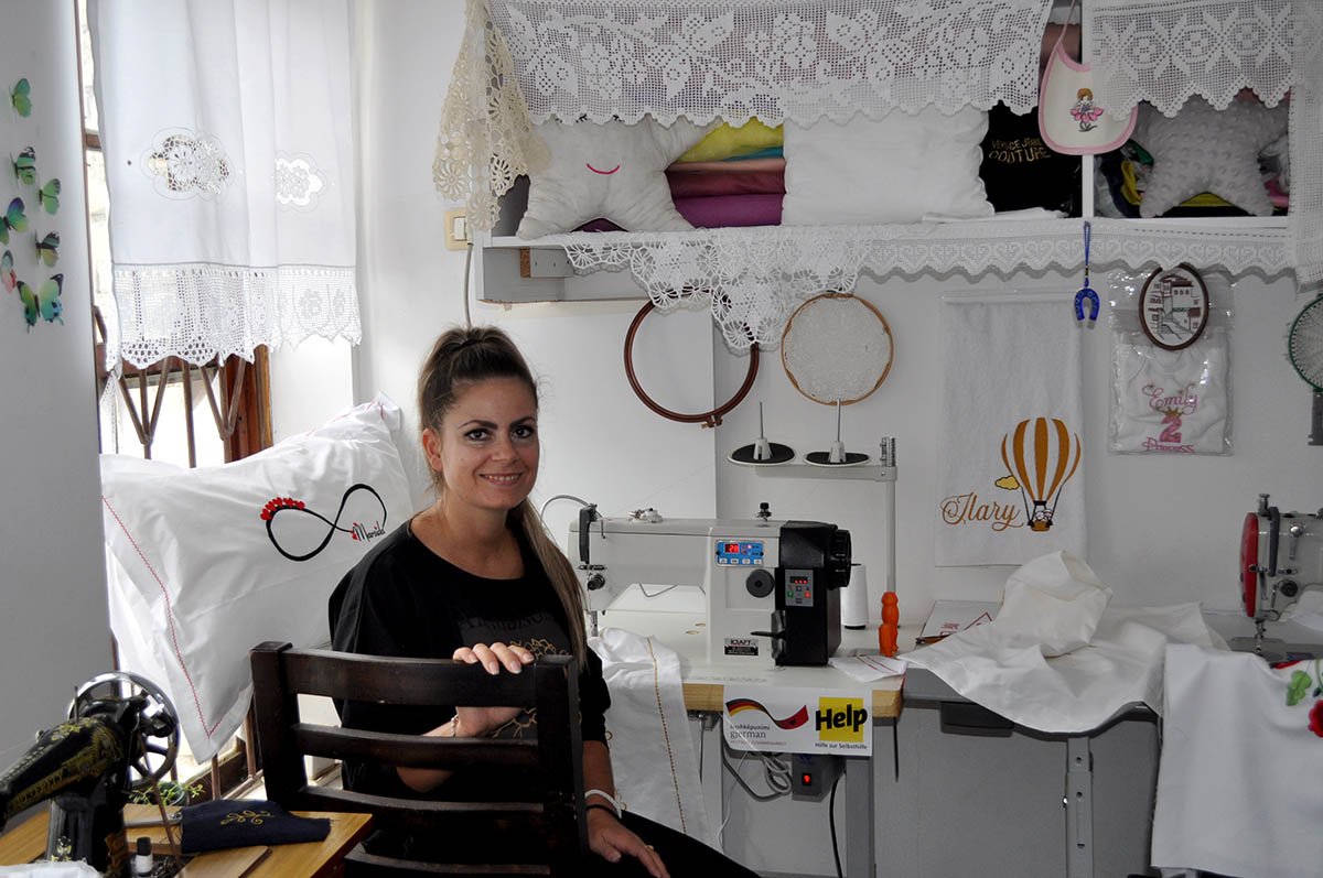 Eine junge Näherin in Albanien freut sich über ihre neue Nähmaschine.