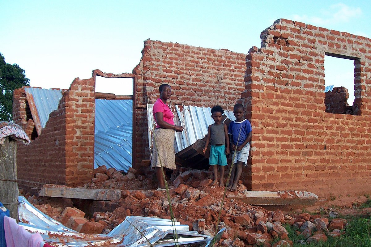 Eine Frau und ihre Kinder stehen vor ihrem zerstörten Haus