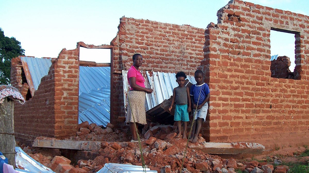 Eine Frau und ihre Kinder stehen vor ihrem zerstörten Haus