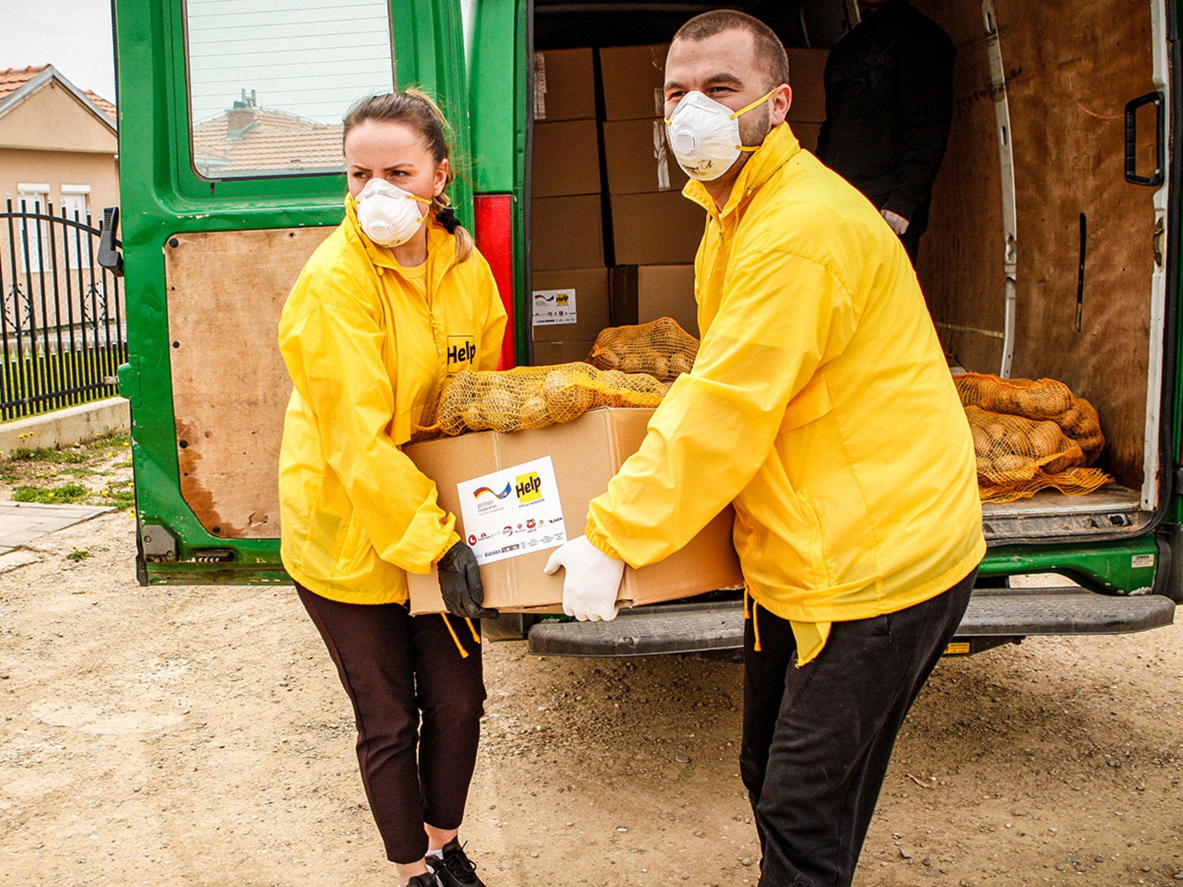 Zwei Help-Mitarbeiter verteilen Lebensmittelpakete im Kosovo