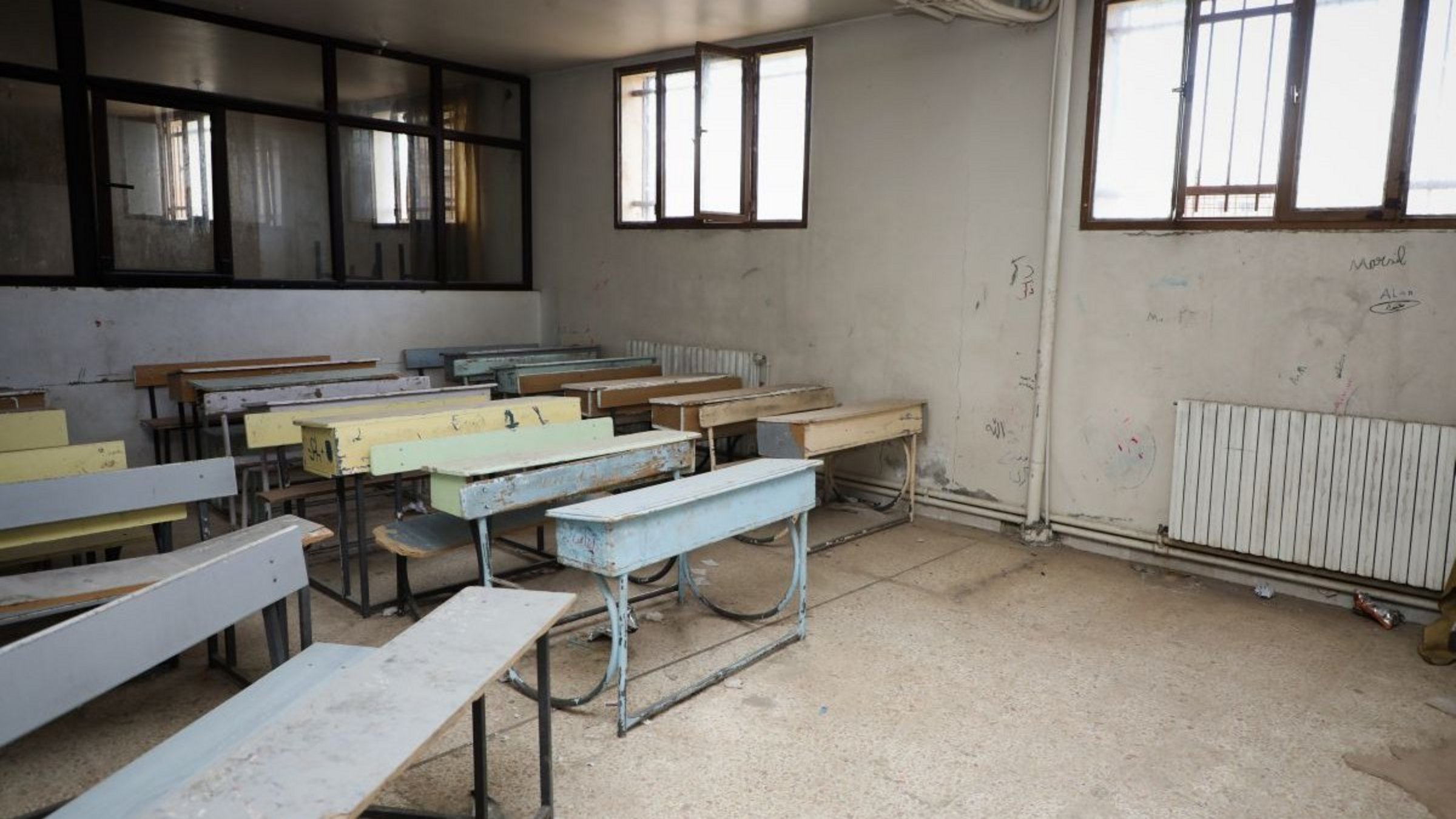 Spenden Syrien: Schulbänke in einem beschädigten Klassenzimmer