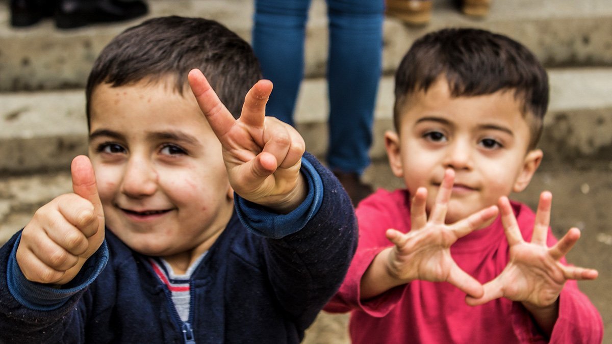 Zwei kleine Jungen machen das Peace-Zeichen und den Daumen nach oben