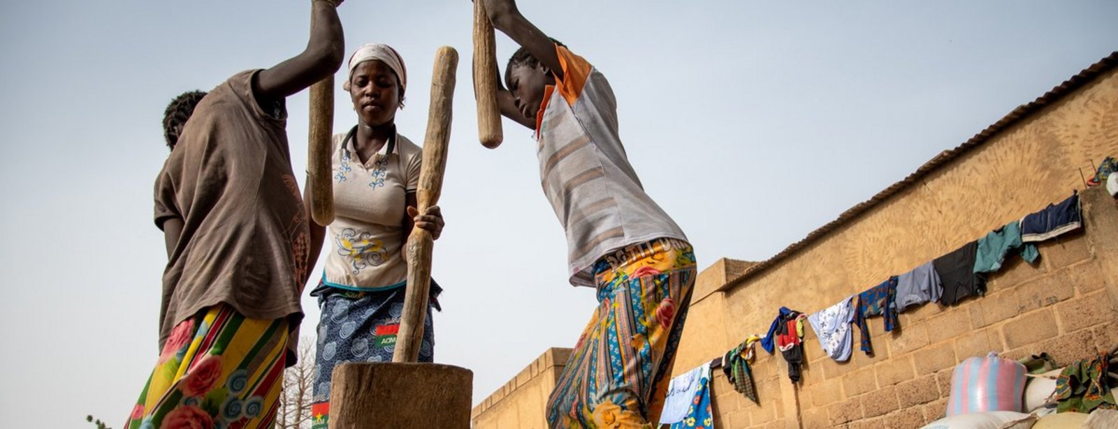Drei Frauen stampfen Getreide in Pissila, Burkina Faso